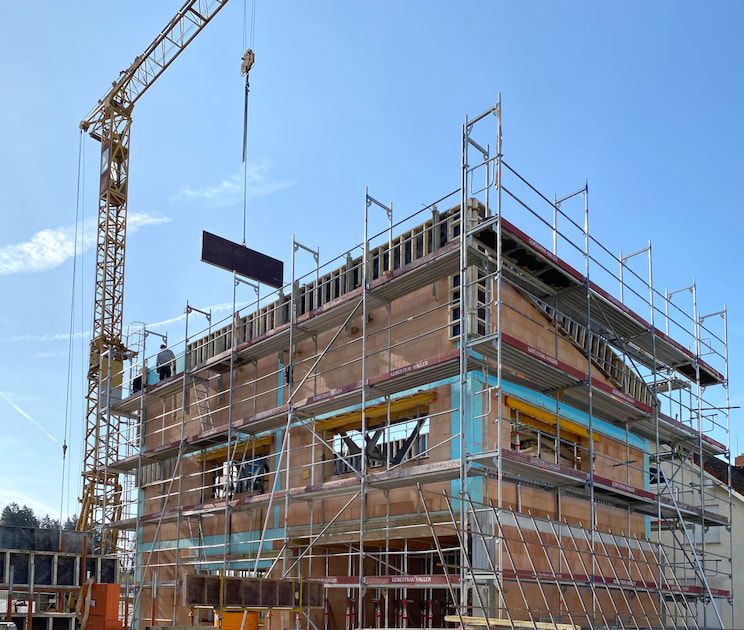 Shell of a building with a crane against blue sky