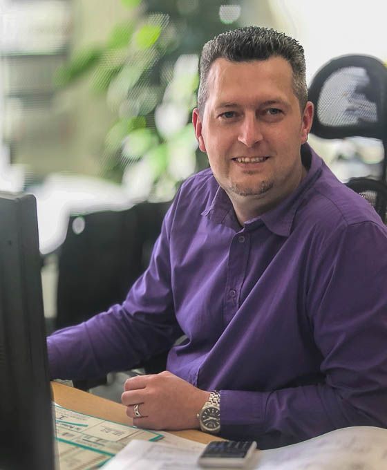 Portrait of a man in a purple shirt at his desk