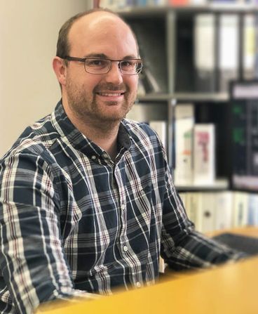 Portrait of a man with glasses at a desk