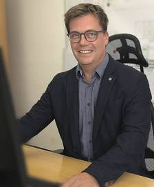 Portrait of a short-haired man wearing a suit coat at a desk