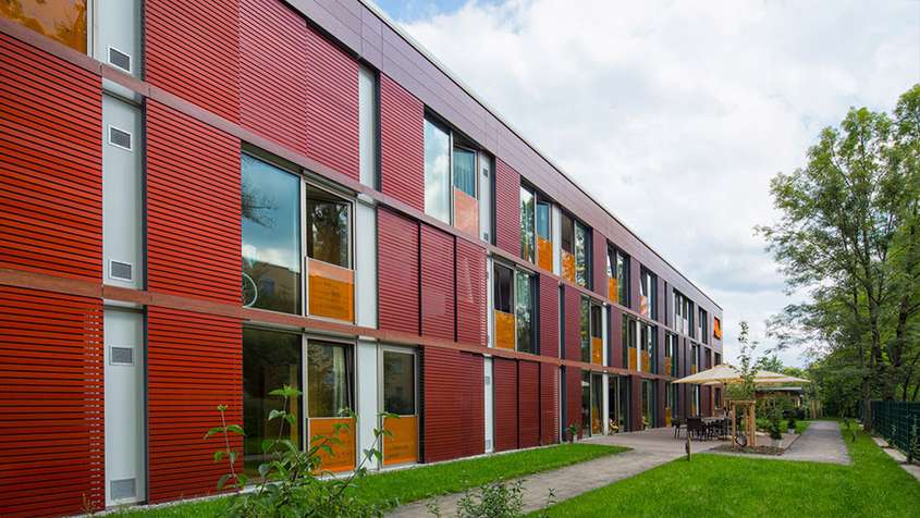 A red facade with a green lawn and a path in front of it