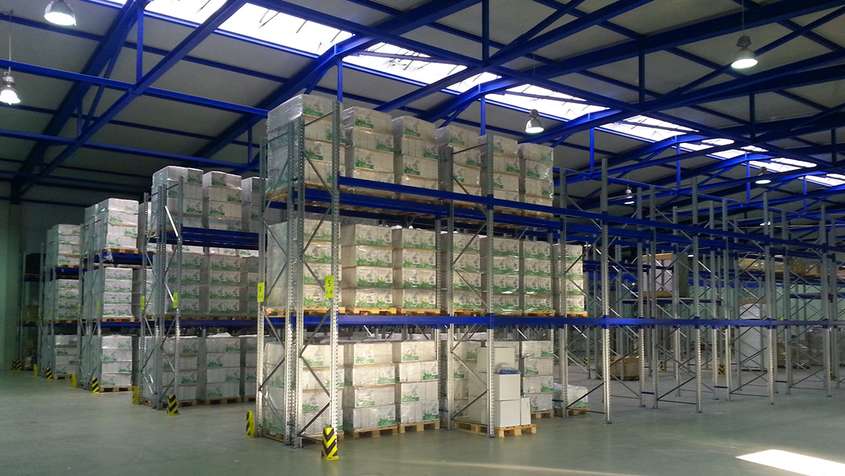 A large warehouse with shelving and blue steel beams