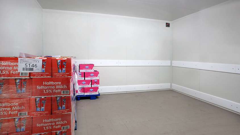 A nearly empty room with white skirting protection strips along the walls