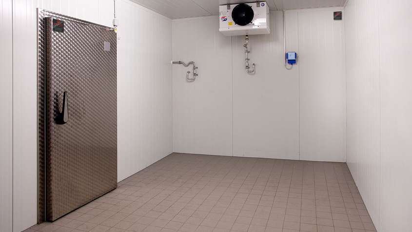 Empty cold storage room with a tiled floor and an AC unit on the ceiling