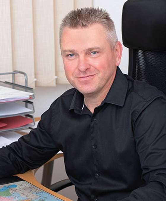 Porträt eines  Mannes in schwarzem Hemd an einem Schreibtisch