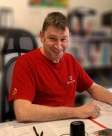 Portrait of a man sitting at a desk wearing a red STADLER sweater