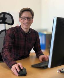 Portrait of a young man with glasses holding a computer mouse