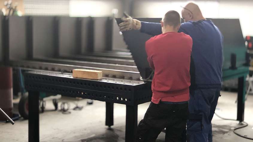 Two men working on a piece of sheet metal together