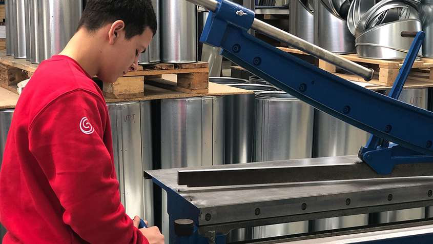 A young man working with a sheet metal processing machine