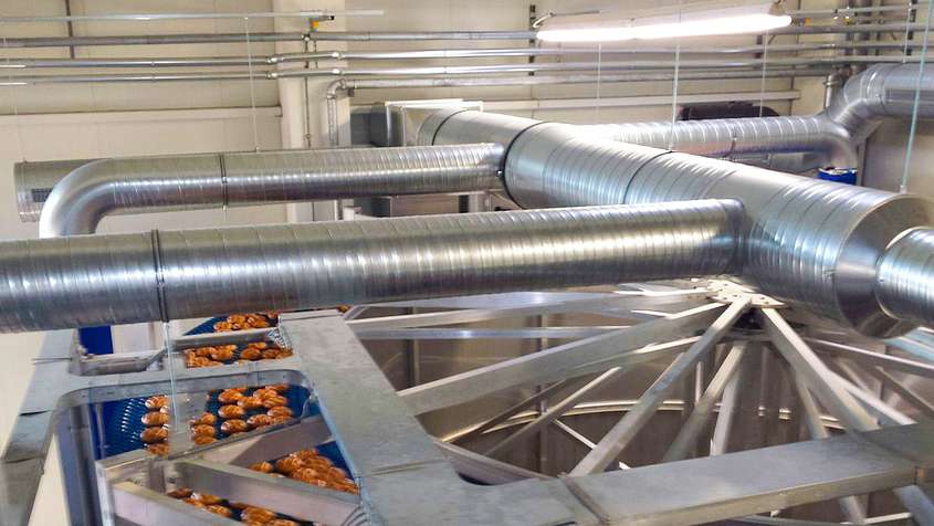 Pipes above a blue conveyor belt carrying breads