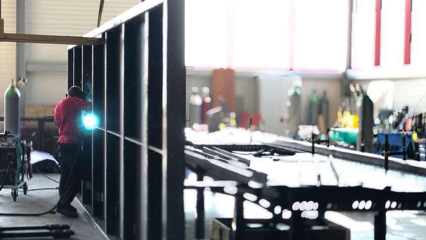 A man welding a metal wall in a workshop