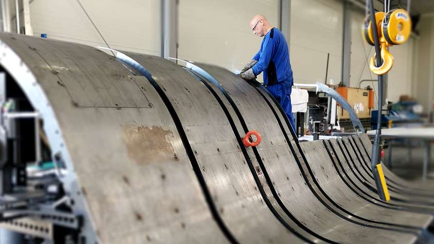 A man working on large, wavy metal pieces