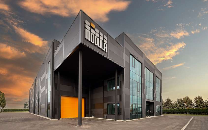 Perspektivansicht eines modernen Industriegebäudes vor einem Sonnenuntergang.