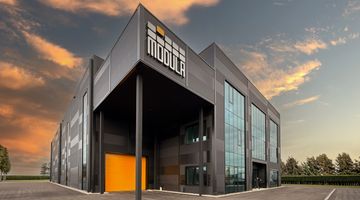 Perspektivansicht eines modernen Industriegebäudes vor einem Sonnenuntergang.