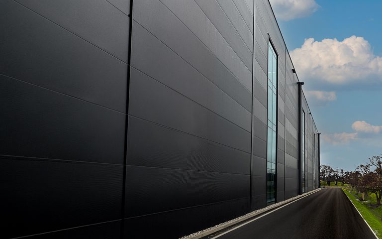 Seitenansicht eines modernen Industriegebäudes mit einer Zufahrtsstraße.