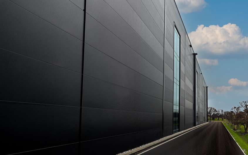 Seitenansicht eines modernen Industriegebäudes mit einer Zufahrtsstraße.