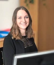 Portrait of a young woman holding a document while sitting at a desk