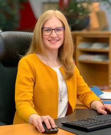 Portrait of a young woman holding a document while sitting at a desk