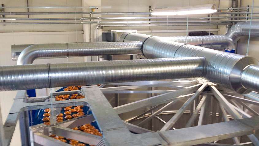 Pipes above a blue conveyor belt carrying bread