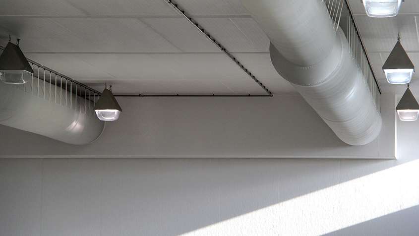 A ceiling with white pipes and hanging lamps